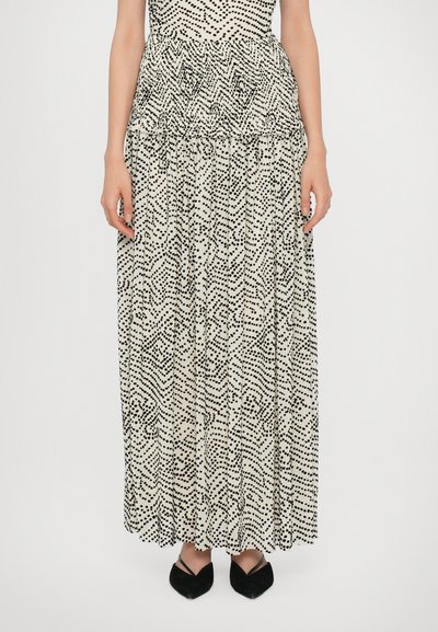 Maxi-jurk met een nauwsluitende top, zwart-wit abstract stippenpatroon, gerimpelde taille en vloeiende rok, gecombineerd met zwarte puntige ballerina's.