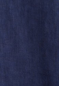 Tessuto in lino blu scuro con una superficie texturizzata, caratterizzato da un sottile motivo di intreccio. L'aspetto generale è solido, senza motivi visibili.