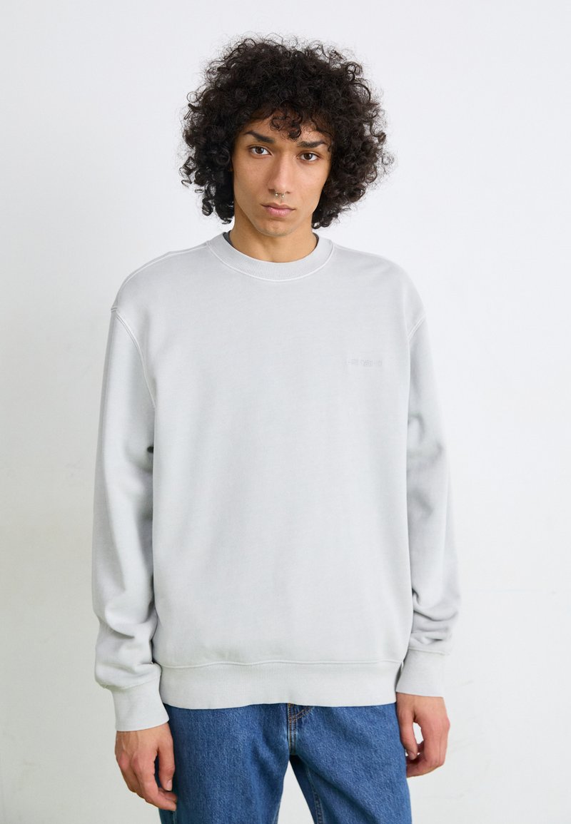 Lysgrå sweatshirt lavet af blødt stof, med rund halsudskæring og ribbede manchetter. Designet er enkelt, uden synlige mønstre eller logoer.
