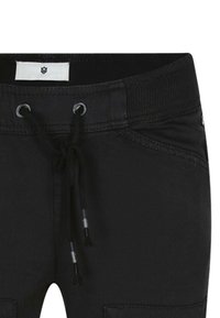 Pantalons en mélange de coton noir avec une taille élastique, fermeture à cordon de serrage, poches latérales et détails de couture subtils.