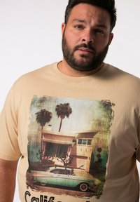 Béžové bavlněné tričko s retro grafikou tyrkysového vintage auta a domu s palmami, zdůrazňující nostalgické téma Kalifornie.