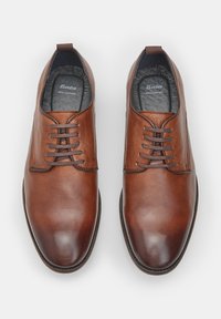 Scarpe in pelle marrone con una superficie liscia, punta arrotondata e design con cinque occhielli per lacci. La fodera interna è grigia scura, contrassegnata "Bata Pelle Reale."
