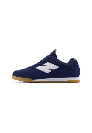 Navy blue athletic shoe with white accents, suede and synthetic upper, round toe, rubber gum sole, and textured detailing on sides.
