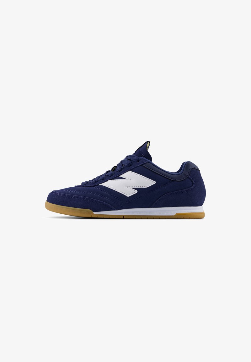Scarpa sportiva blu navy con dettagli bianchi, tomaia in suede e sintetico, punta rotonda, suola in gomma, e dettagli testurizzati sui lati.