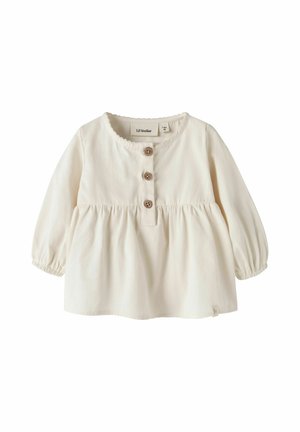 Blouse bébé crème à manches longues avec taille froncée, encolure ronde, trois boutons marron sur le devant et poignets élastiques.