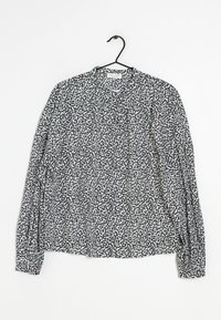 Blusa a maniche lunghe con motivo a pois bianco e nero, tessuto leggero, scollatura rotonda e maniche raccolte con polsini elasticizzati.