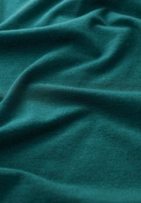 Teal tkanina s mekom, glatkom teksturom, prikazana u nabranim slojevima, ističući ujednačenu boju i suptilni sjaj. Nema uzoraka niti značajnih hardverskih elemenata.