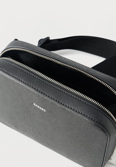 Μαύρη υφασμάτινη ορθογώνια τσάντα χιαστί με ασημί φερμουάρ και ρυθμιζόμενο υφασμάτινο λουρί, μερικώς ανοιχτή που αποκαλύπτει την εσωτερική επένδυση.