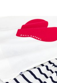 T-shirt blanc avec un grand motif de cœur rouge et le texte "petit bateau", superposé sur un short rayé bleu marine et blanc. Tissu en coton doux.