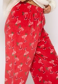 R�öda pyjamasbyxor i mjukt tyg, med ett upprepat mönster av skissade cocktailglas med gröna julsymboler. Löst snitt med elastiskt midjeband.