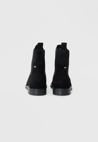 Stivaletti neri in suede con pannelli laterali elasticizzati e linguette, dotati di una suola in gomma nera e piccolo logo accentato sul retro.
