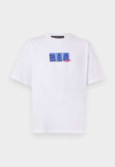 T-shirt en coton blanc avec une impression graphique bleue comportant trois images architecturales et du texte rouge sur le devant. Encolure ronde et manches courtes.