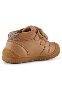 Scarpa per bambini in pelle tan con tomaia morbida, cinturini in Velcro e accento testurizzato sul tallone. Presenta una suola in gomma flessibile con motivo a battistrada.