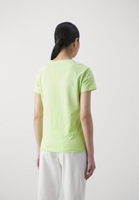 Jasnozielona bawełniana koszulka z krótkim rękawem i okrągłym dekoltem, wyświetlona z tyłu, charakteryzująca się gładką fakturą.