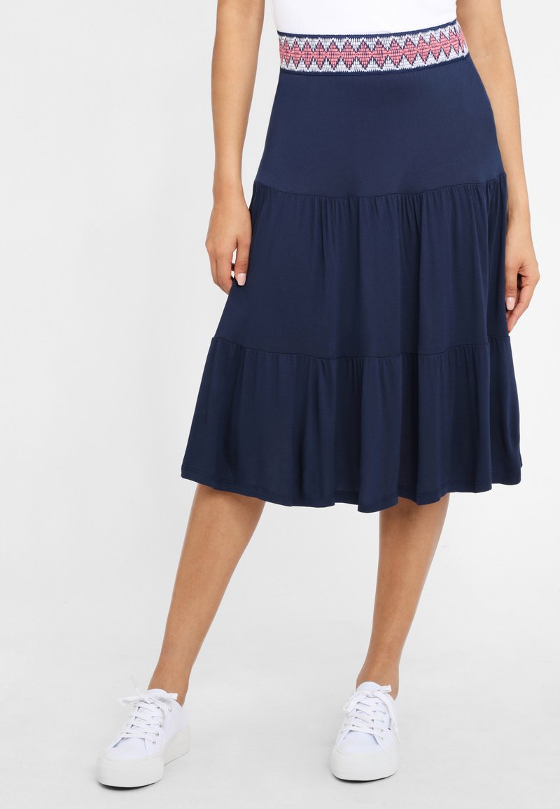 Marineblauwe tiered rok met een patroon op de elastische tailleband. Gemaakt van zachte materialen, heeft het een vloeiend ontwerp en subtiele ruffles aan de onderrand.