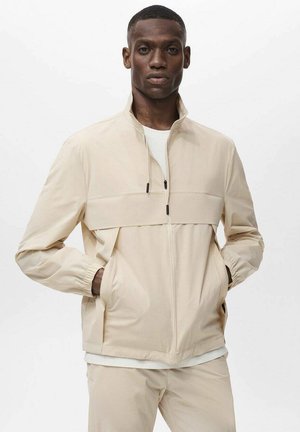 Beige zip-up jacket made of lightweight fabric, featuring a high collar, elastic cuffs, two side pockets, and a color-blocked design.
