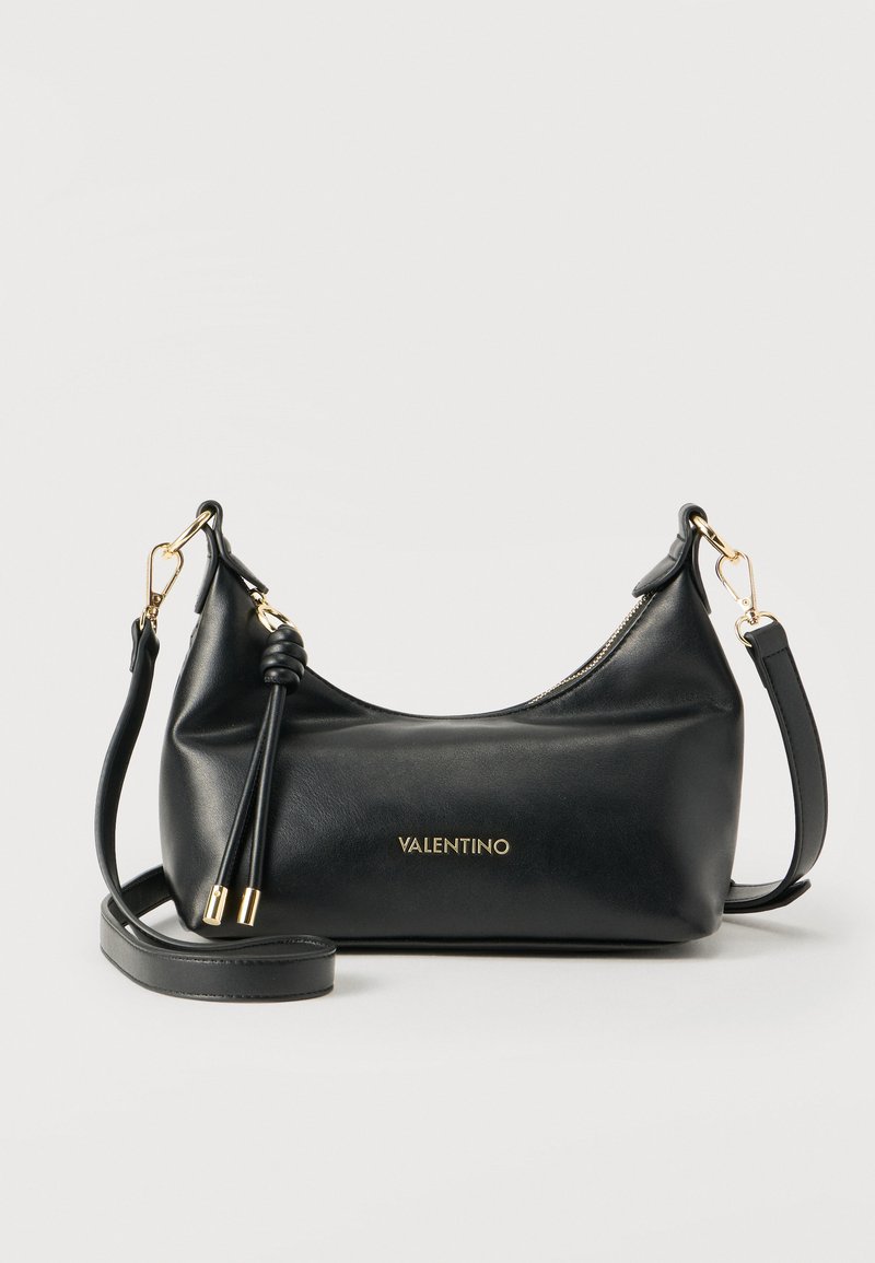 Μαύρη δερμάτινη τσάντα ώμου Valentino με χρυσά μεταλλικά στοιχεία, κλείσιμο με φερμουάρ, διακοσμητικές δερμάτινες φούντες και ρυθμιζόμενο λουρί σε λευκό φόντο.