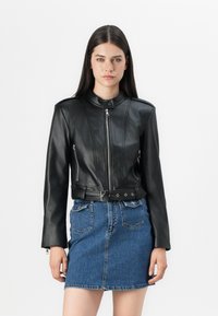 Svart lær cropped jakke med ståkrage, frontlynlås og to med glidelåser, sammen med et blått denim miniskjørt.