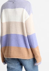 Pull en maille épaisse avec des rayures horizontales en lavande, crème, beige et bleu poussiéreux, à coupe décontractée et avec des finitions côtelées aux poignets.