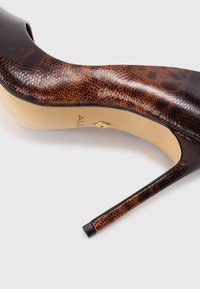 Brown high-heeled shoe with a glossy snake-skin texture, pointed toe, and a slim stiletto heel, featuring a gold accent on the side.