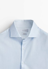 Himmelblaues Hemd mit Knopfleiste aus glattem Stoff, mit strukturiertem Kragen, kurzen Ärmeln und einem subtilen Glanz. Maximo Dutti Etikett sichtbar.