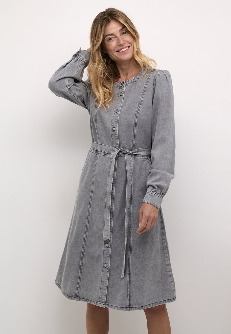 Gray denim dress with long sleeves, button front, and a tie waist. Features subtle vertical stitching and a knee-length hem.