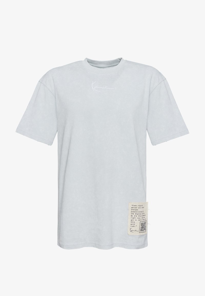 Svetlošedé nadrozmerné tričko s krátkymi rukávmi, malým bielym podpisom na hrudi a béžovou záplatou s textom a QR kódom pri leme.