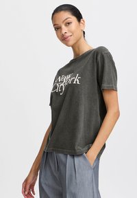 Oversized dark gray t-shirt made of soft fabric, featuring white "New York City" text. Short sleeves, relaxed fit, and a round neckline.