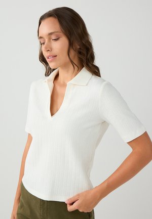 Witte polo met korte mouwen en een V-hals, voorzien van een gestructureerd ribbelpatroon. Heeft een contrasterende kraag en een getailleerd ontwerp.