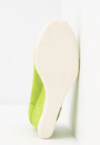 Baskets vertes avec une tige en suède texturé et des détails en mesh. La semelle extérieure est blanche avec un motif en chevrons. Taille indiquée : 37.