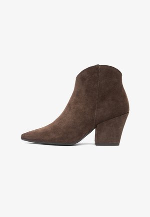 Brązowy zamszowy botek na kostkę z zaostrzonym noskiem i masywnym, średniej wysokości obcasem, z bocznym zamkiem, widoczny od zewnętrznej strony.