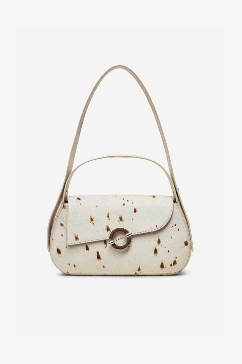 Sac à main couleur crème avec des taches marron, rabat incurvé avec une fermeture métallique circulaire, doté de deux fines anses, dont une plus longue pour porter à l'épaule.