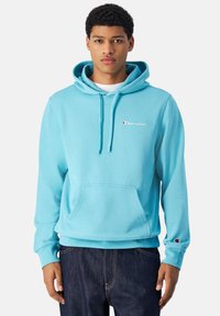 Sudadera azul claro con un bolsillo frontal, capucha con cordón y logo bordado en el pecho. Tejido de algodón, corte holgado, puños acanalados.