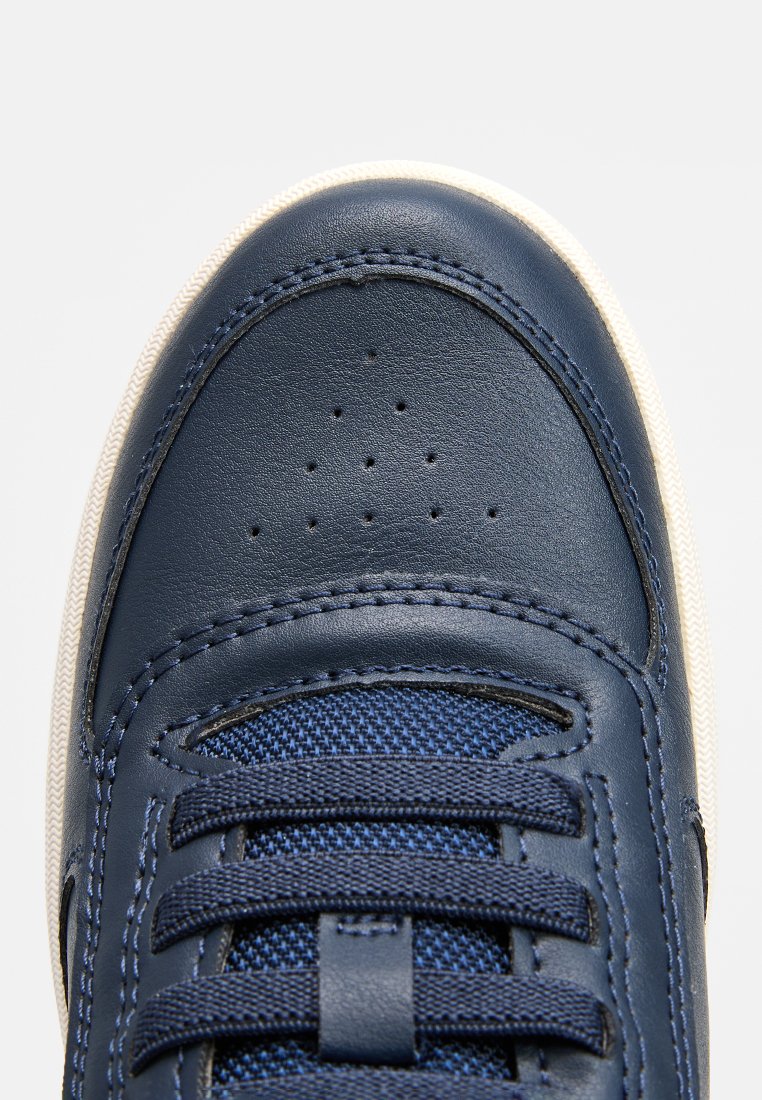 Marinblå lädersneakers med texturerade canvaspaneler, rund tå, sex ögla och krämfärgad sula. Har perforerad tåkappa och sydda detaljer.
