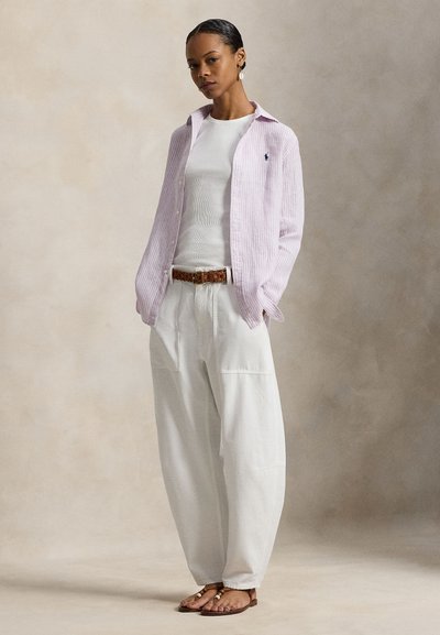 Ανοιχτό μοβ ριγωτό πουκάμισο με κουμπιά, λευκή ριμπ μπλούζα χωρίς μανίκια, μπεζ παντελόνι με φαρδιά πόδια, καφέ πλεκτή ζώνη, χρυσά σανδάλια με λεπτομέρειες.