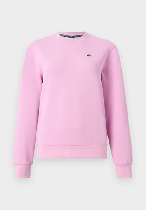 Gaiši rozā garām piedurknēm džemperis ar apaļu kakla izgriezumu, ribota aproču un apakšmalas apdare, teksturēts audums, mazs zaļš krokodila logotips kreisajā krūtīs.