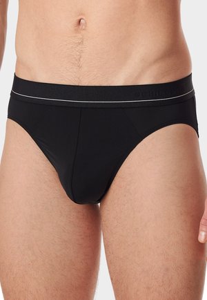 Slip neri da uomo con una superficie liscia, cintura elastica con un logo sobrio e una linea bianca accentuata, progettati con una silhouette aderente.