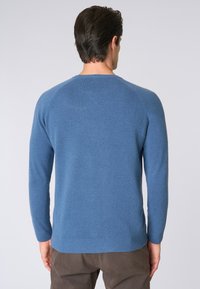 Maglione blu a collo tondo realizzato in materiale morbido, con maniche lunghe e orlo a coste. Texture liscia con un design semplice e di colore solido.