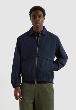 Marineblauwe zip-up jack met een ritssluiting aan de voorkant, twee voorvakjes en elastische manchetten. Gladde stof met een ontspannen pasvorm en een kraagontwerp.