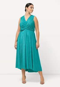 Vestido sin mangas en color azul verdoso con escote en V, cuerpo retorcido y textura plisada. Llega por debajo de la rodilla con una silueta fluida en A.