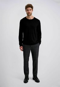 Schwarzes Langarmshirt kombiniert mit grauen karierter Hose und schwarzen Schnürschuhen. Das Outfit weist ein einfaches, strukturiertes Design auf.