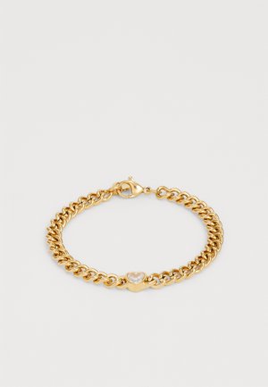 Bracelet en chaîne dorée avec un pendentif en forme de cœur en pierre précieuse transparente et un fermoir à lobster sur fond blanc uni.