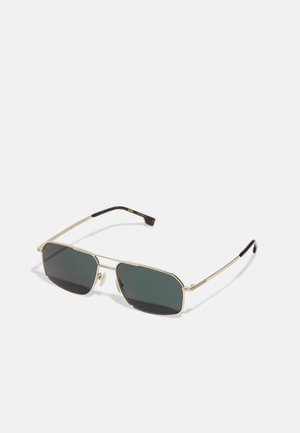 Gafas de sol con un marco de metal dorado, forma rectangular, lentes de color verde oscuro y un diseño elegante con puntas negras en las varillas.