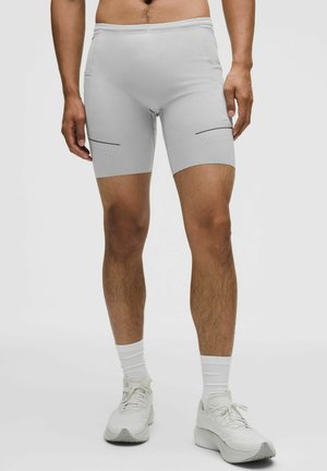 Hellgraue Sportshorts aus dehnbarem Material mit zwei seitlichen Reißverschlusstaschen, horizontalen schwarzen Akzenten und figurbetontem Design.