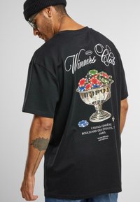 Black cotton t-shirt featuring a graphic of a trophy filled with colorful poker chips and the text "Winners Club" above it.