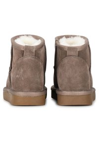 Botas de ante marrón hasta el tobillo con un suave forro interior blanco, que presentan un tacón redondo y detalles de costura lateral.