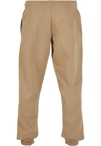 Beige bomulls joggebukser med en avslappet passform, elastisk midje og mansjetter. Har en baklomme for ekstra nytte.