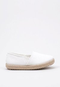 Zapato tipo slip-on de lona blanca con punta redonda, aberturas elásticas y suela de yute trenzado. Diseño minimalista con una textura suave.