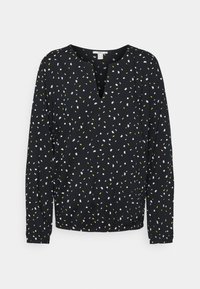 Zwarte blouse met een V-hals, lange mouwen en een geplooide zoom. Heeft een verspreid patroon van witte en gele accenten. Lichtgewicht stof.