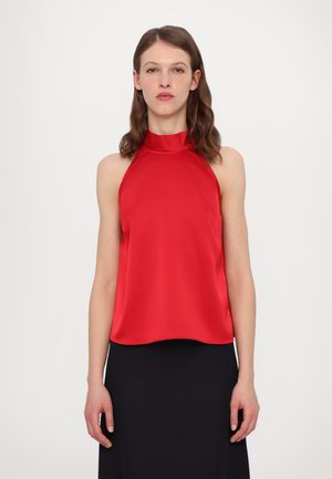 Rød halterneck topp laget av glatt stoff, med en avslappet passform, bølget nederkant og minimalistisk design. Kombinert med et svart skjørt.